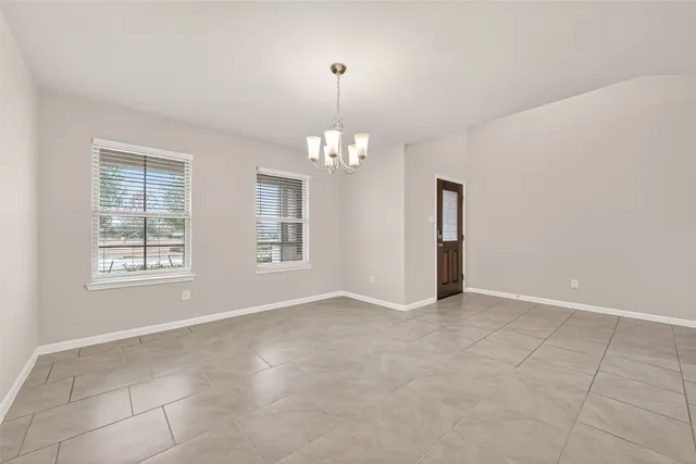 an empty room with chandelier and windows