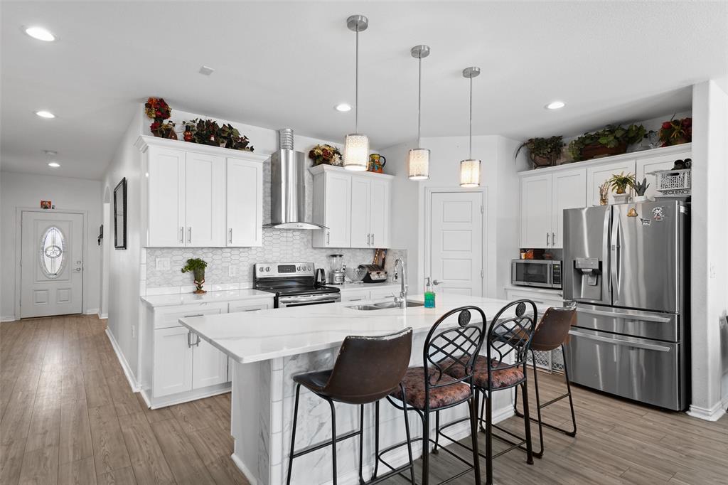 0 Ewing Road Ferris, TX 75125 - Photo 5 of 29 Open-concept kitchen with white cabinetry, stainless steel appliances, a center island with pendant lighting, and wood-finish flooring