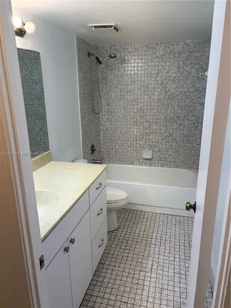 a bathroom with a granite countertop bathtub shower sink and toilet