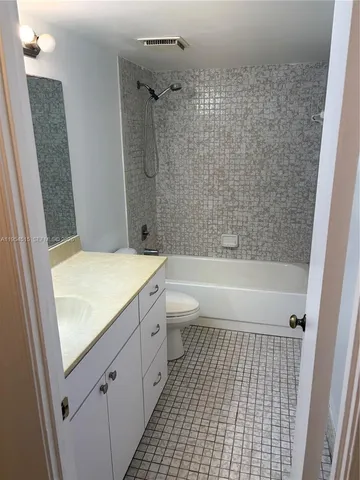 a bathroom with a granite countertop bathtub shower sink and toilet