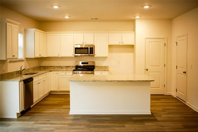 a large kitchen with stainless steel appliances granite countertop a stove a sink and white cabinets