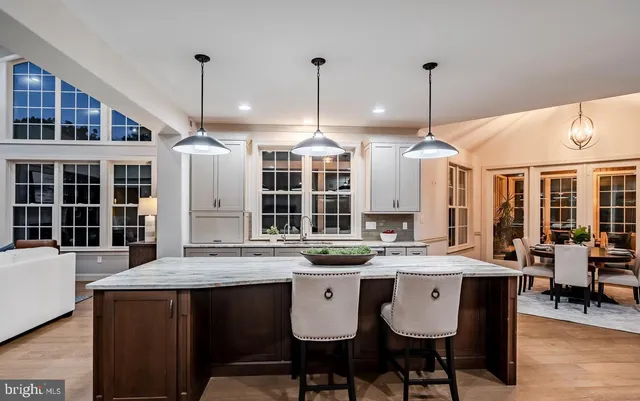 a kitchen with stainless steel appliances a sink a stove a window and chairs