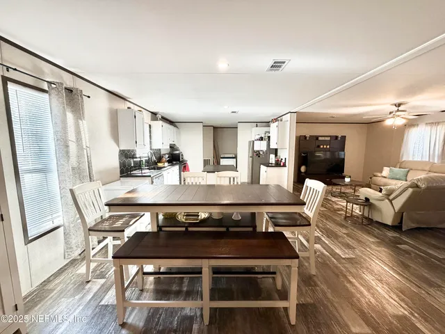 a view of a kitchen with stainless steel appliances granite countertop a stove a refrigerator a dining table and chairs with wooden floor