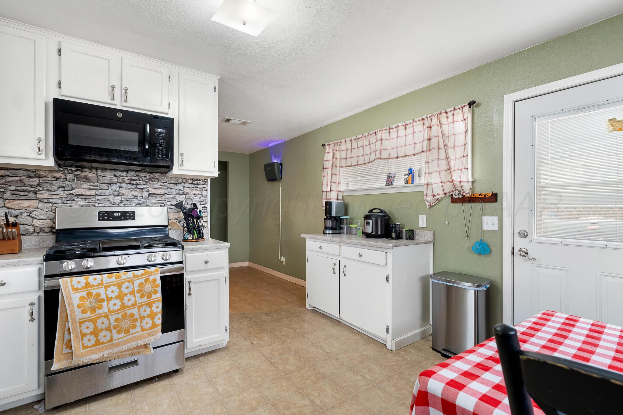 4603 Parker Street Amarillo, TX 79110 - Photo 7 of 20 a kitchen with a stove a sink and a microwave