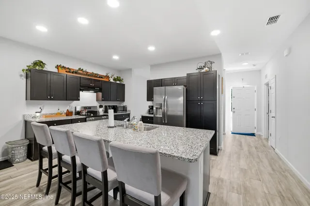 a large kitchen with stainless steel appliances a stove a sink dishwasher a dining table and chairs with wooden floor