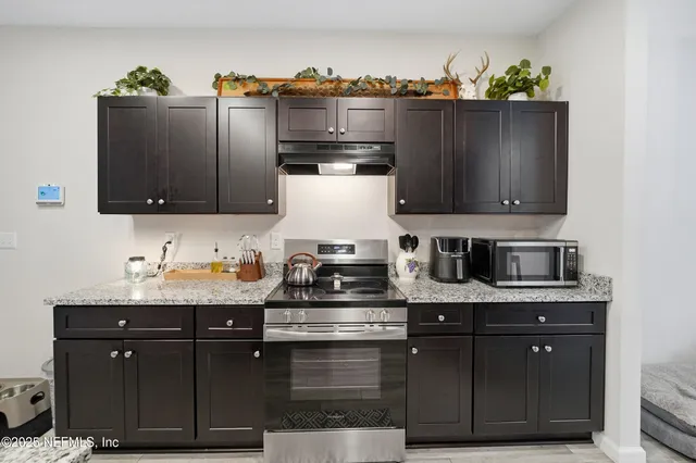 a kitchen with stainless steel appliances granite countertop a refrigerator a stove and a sink with wooden floor