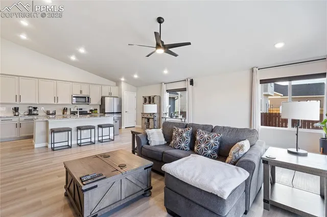 a living room with furniture kitchen view and a wooden floor
