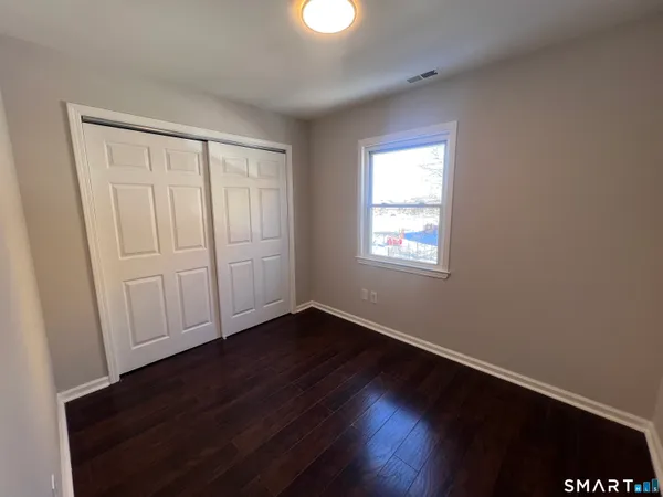 an empty room with wooden floor cabinet and windows