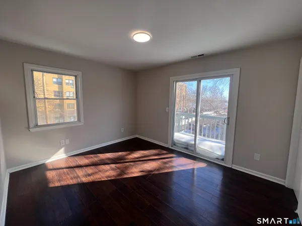 a view of an empty room with wooden floor and a window