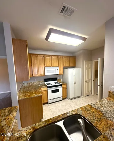 a kitchen with granite countertop a refrigerator stove and sink