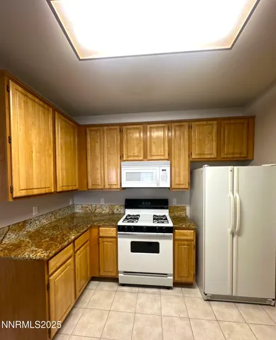 a kitchen with granite countertop a stove a sink and a refrigerator