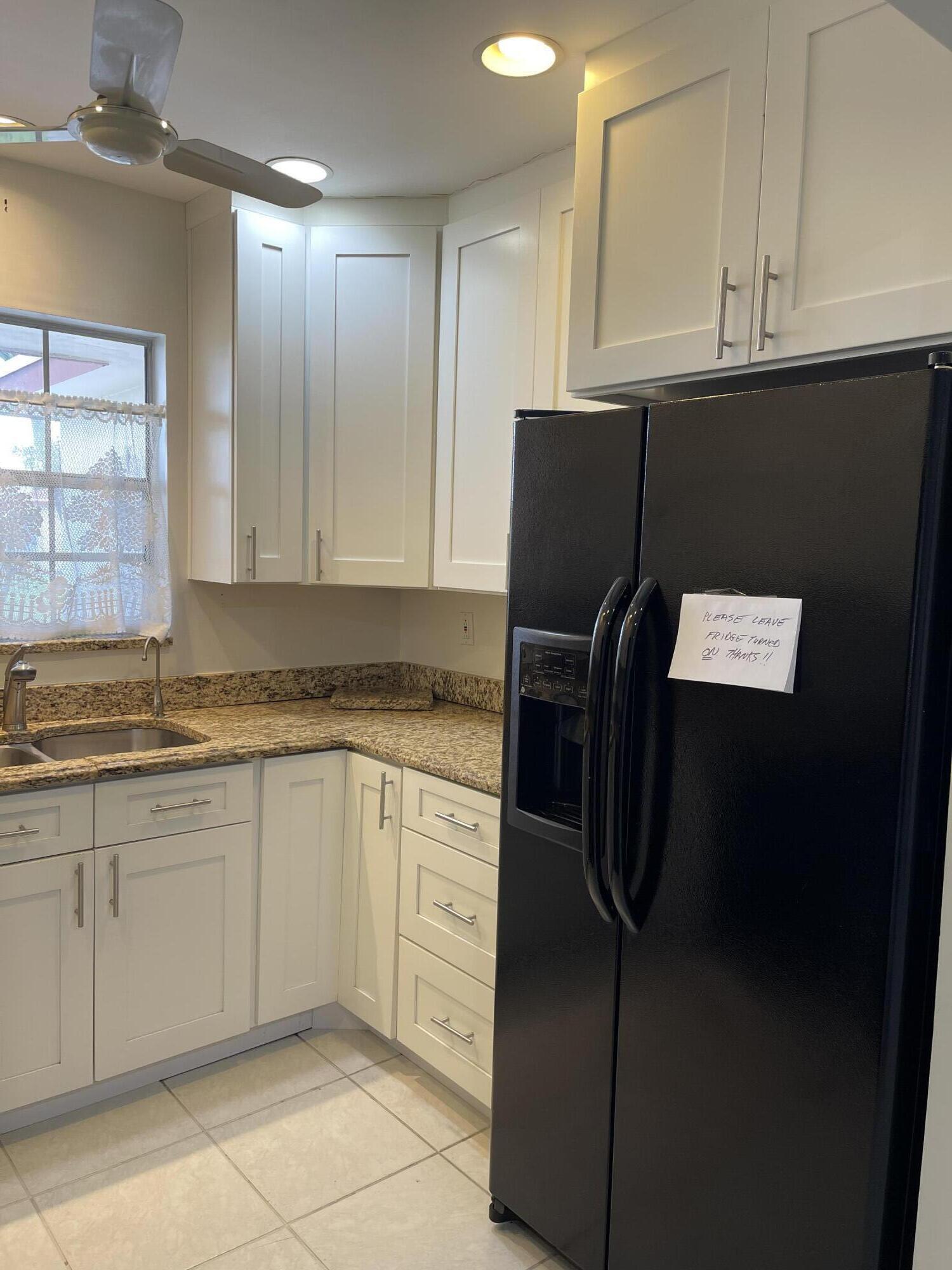 4530 Northwest 2nd Street, Unit D Delray Beach, FL 33445 - Photo 8 of 31 a kitchen with granite countertop a refrigerator and a sink