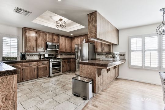 928 Randall Street Ridgecrest, CA 93555 - Photo 3 of 34 a kitchen with stainless steel appliances granite countertop a stove top oven a sink dishwasher a dining table and chairs with wooden floor