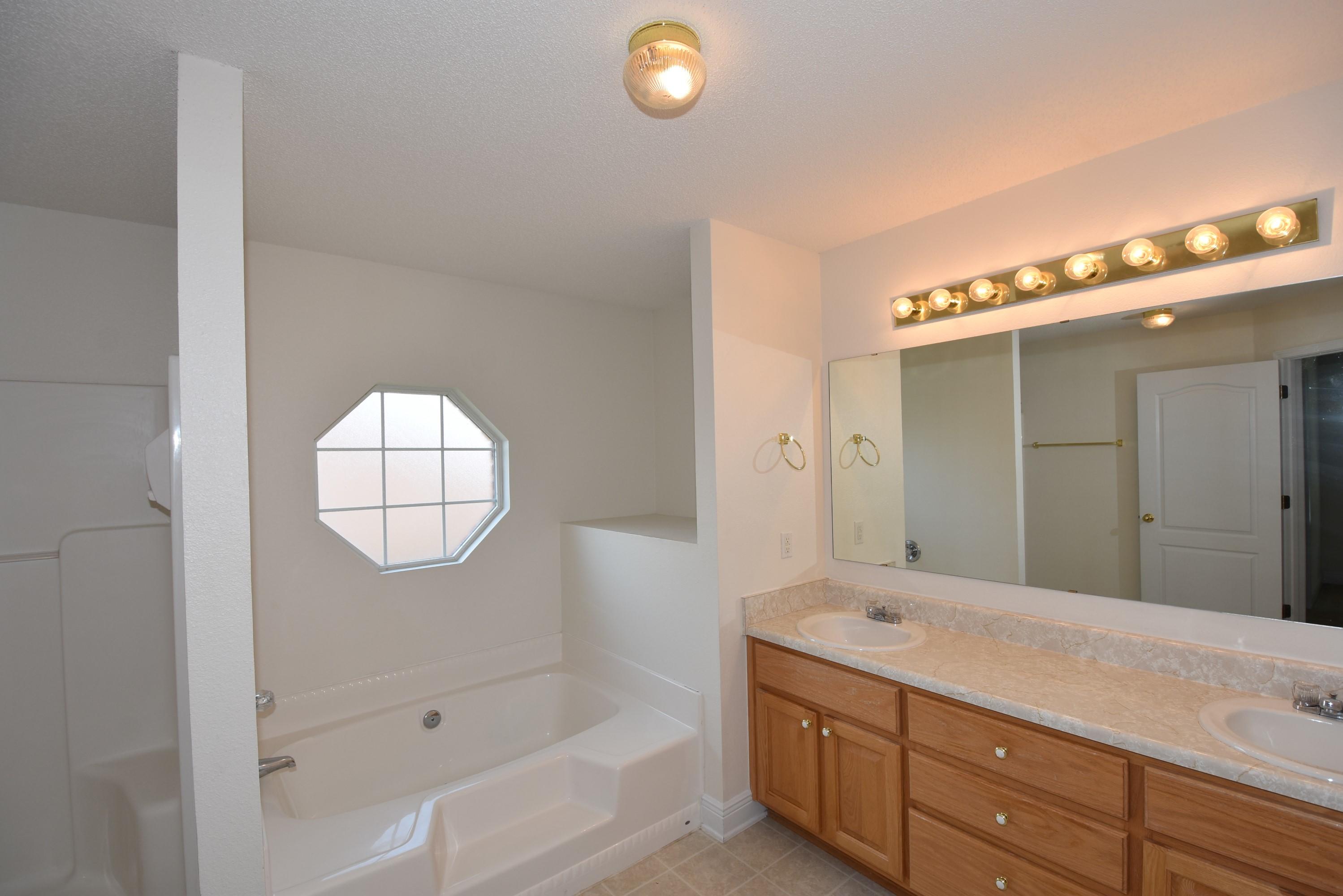 404 Swift Fox Run Crestview, FL 32536 - Photo 21 of 37 a bathroom with a sink a vanity a mirror a bathtub and shower
