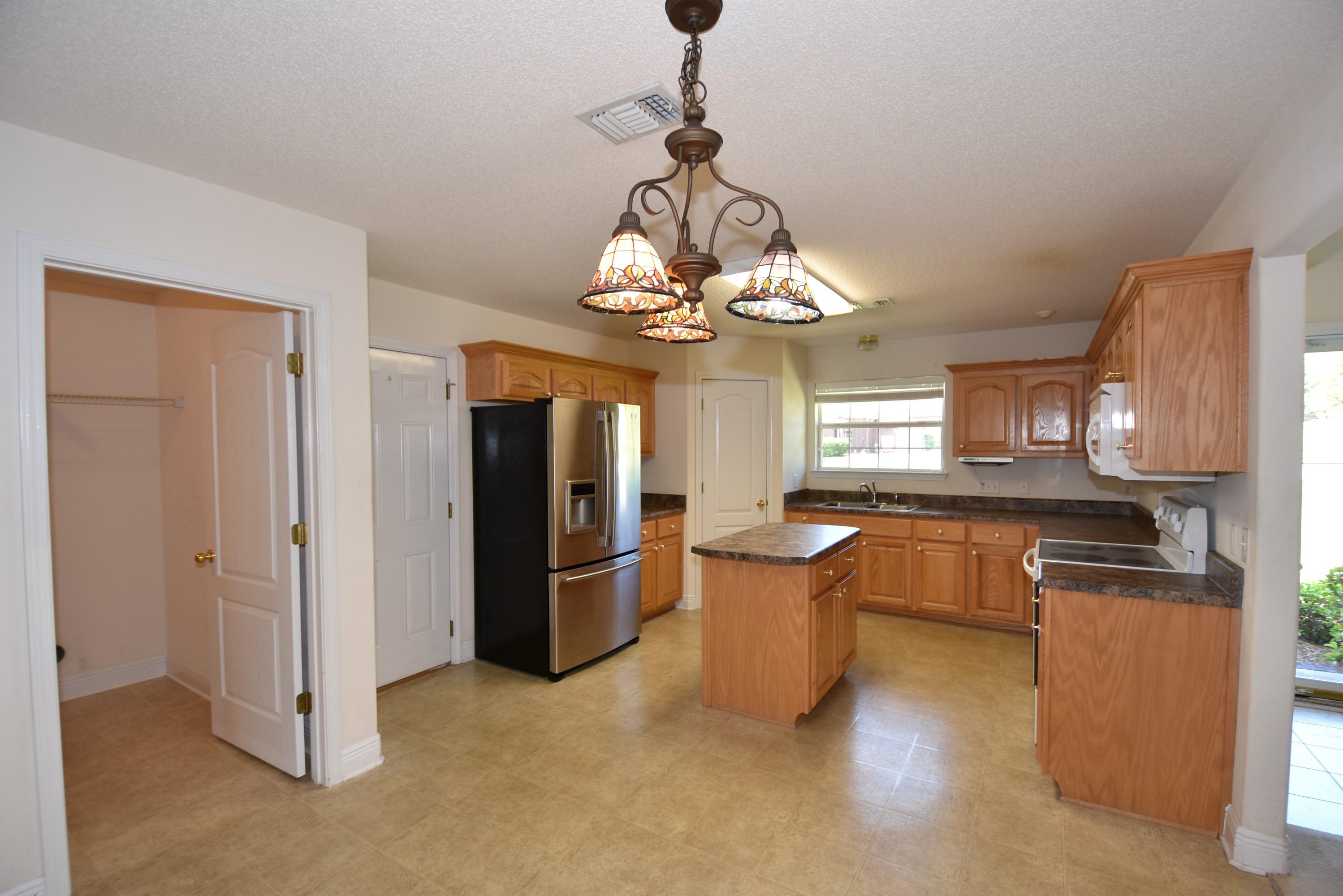 404 Swift Fox Run Crestview, FL 32536 - Photo 7 of 37 a dining room with wooden floor a chandelier a wooden table and chairs