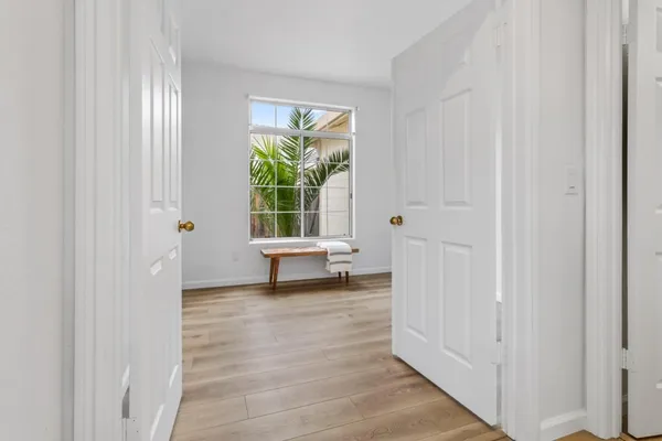 a view of a hallway with wooden floor and a livingroom with furniture