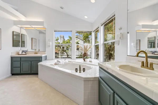 a spacious bathroom with a tub double sink and mirror