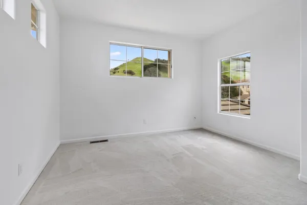 an empty room with windows and refrigerator