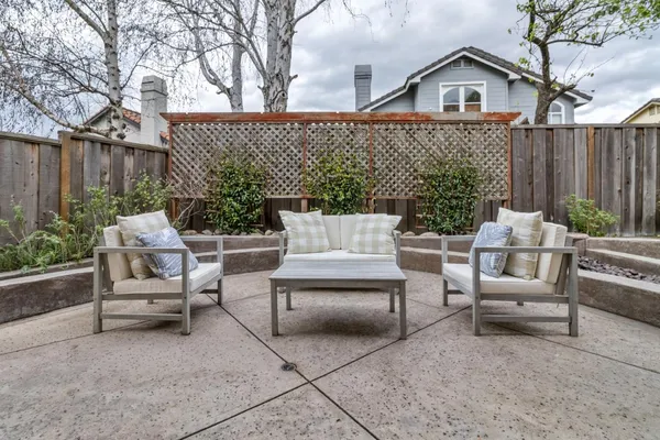 a view of a patio with couches and a table and chairs with wooden fence