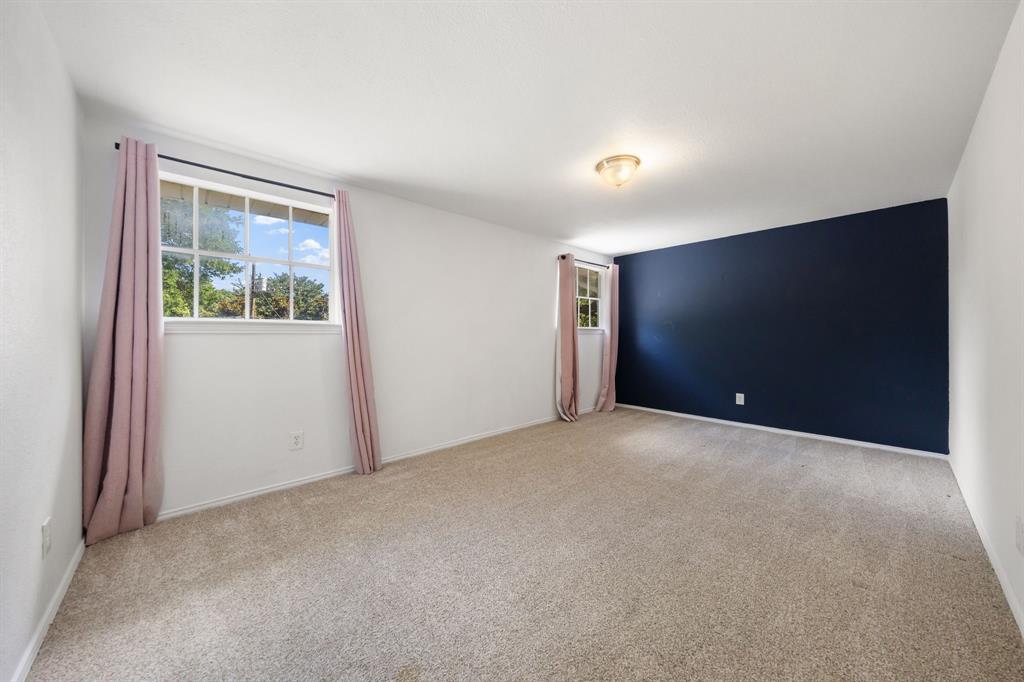 3060 Timberview Road Dallas, TX 75229 - Photo 25 of 39 Spacious interior room featuring light-toned carpeting, a prominent accent wall in a deep navy hue, and white painted walls