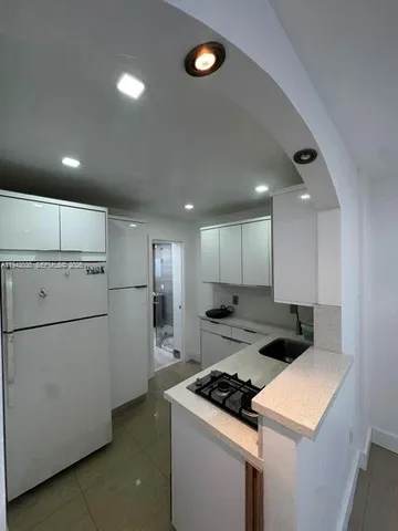 a kitchen that has a refrigerator a stove and white cabinets