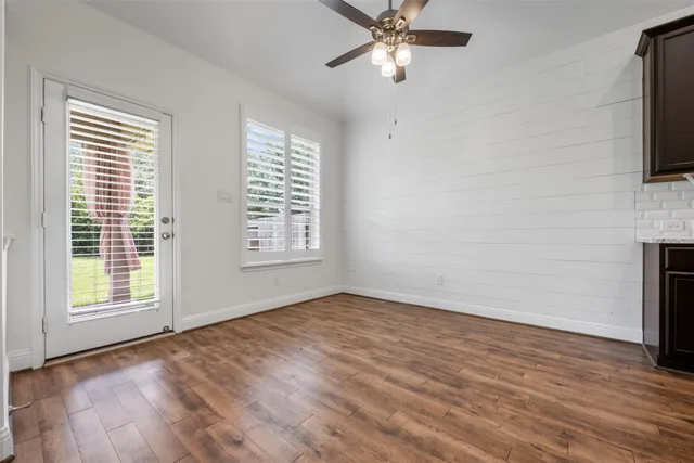 a view of an empty room with a window and wooden floor