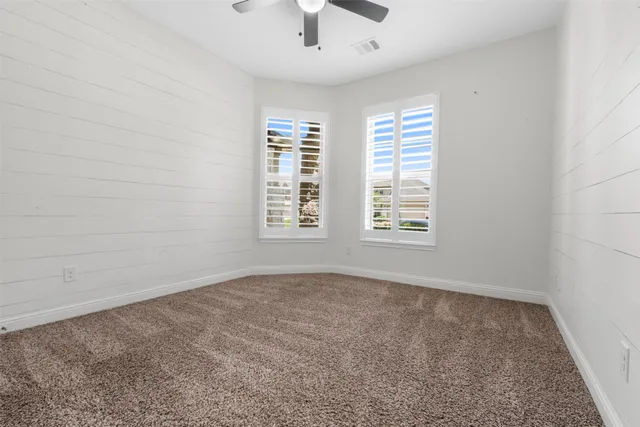 an empty room with a window and a ceiling fan