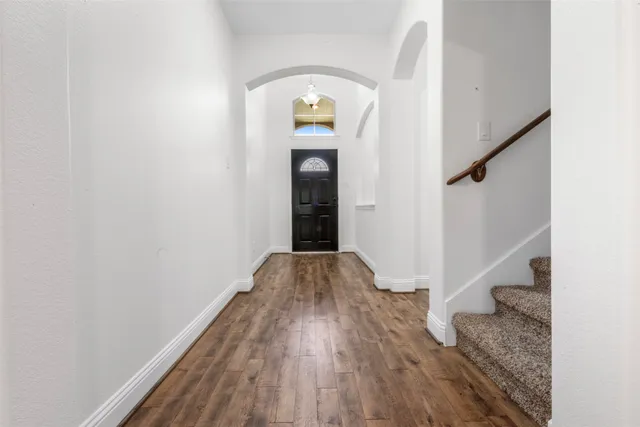 a view of a hallway with wooden floor and staircase