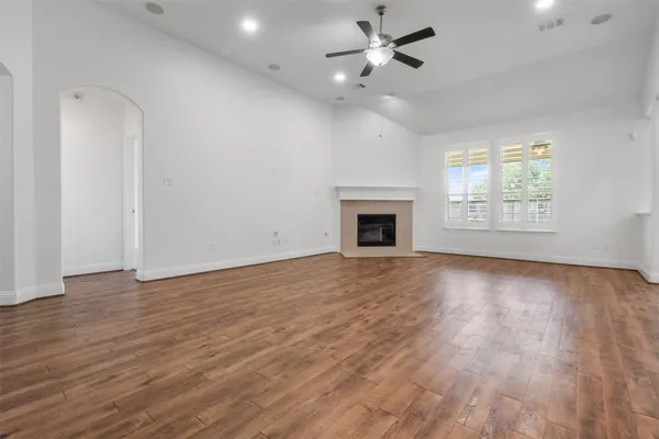 a view of an empty room with wooden floor and a fireplace