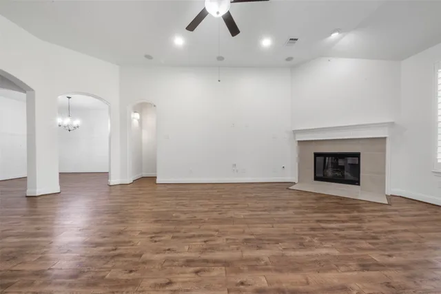 a view of an empty room with wooden floor and a fireplace