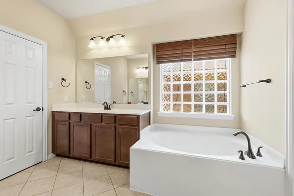 a spacious bathroom with a tub sink and mirror