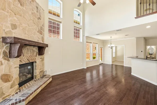 a view of an empty room with wooden floor and a fireplace