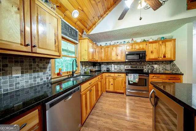 a kitchen with stainless steel appliances a sink dishwasher a stove top oven a refrigerator and cabinets with wooden floor