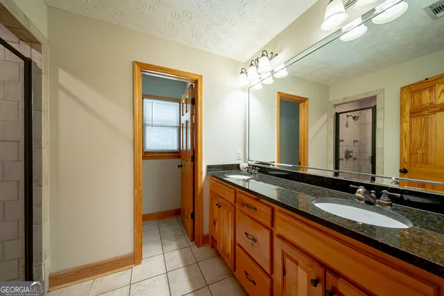 a spacious bathroom with a granite countertop sink a mirror and a shower
