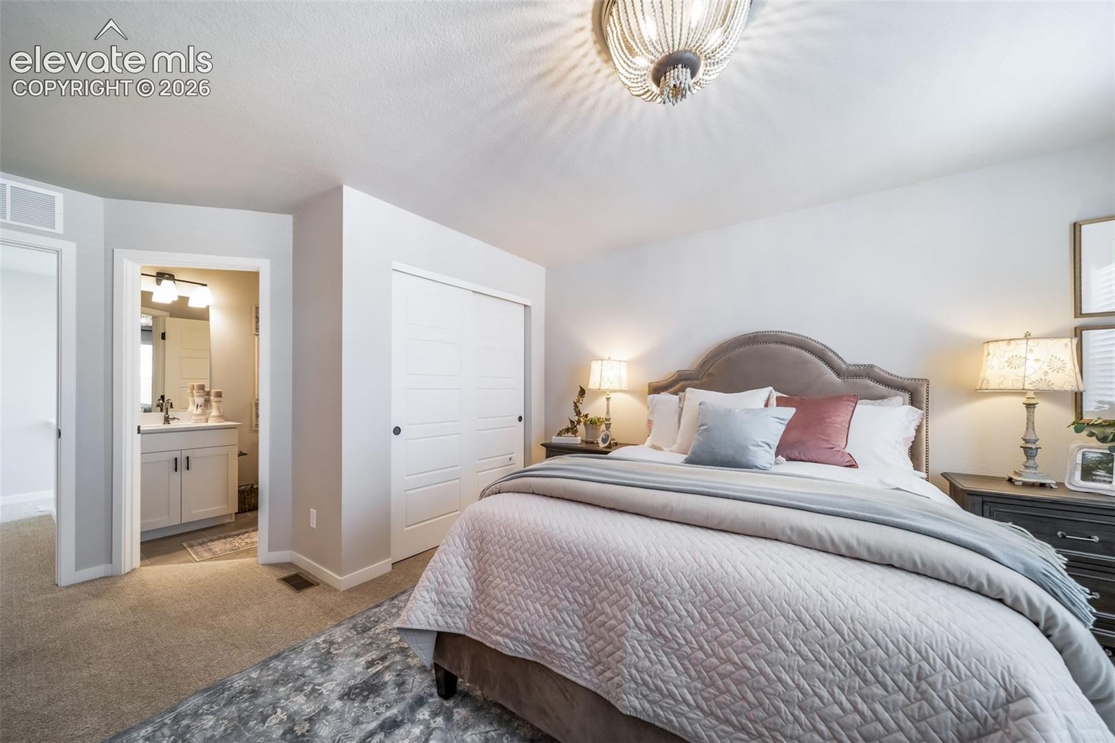 4876 Truscott Road Colorado Springs, CO 80925 - Photo 5 of 28 Bedroom featuring carpet flooring, an upholstered headboard, and a beaded semi-flush mount ceiling light
*Photos of a model home*