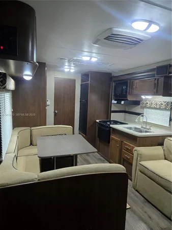 a living room with stainless steel appliances kitchen island a cabinets and wooden floor