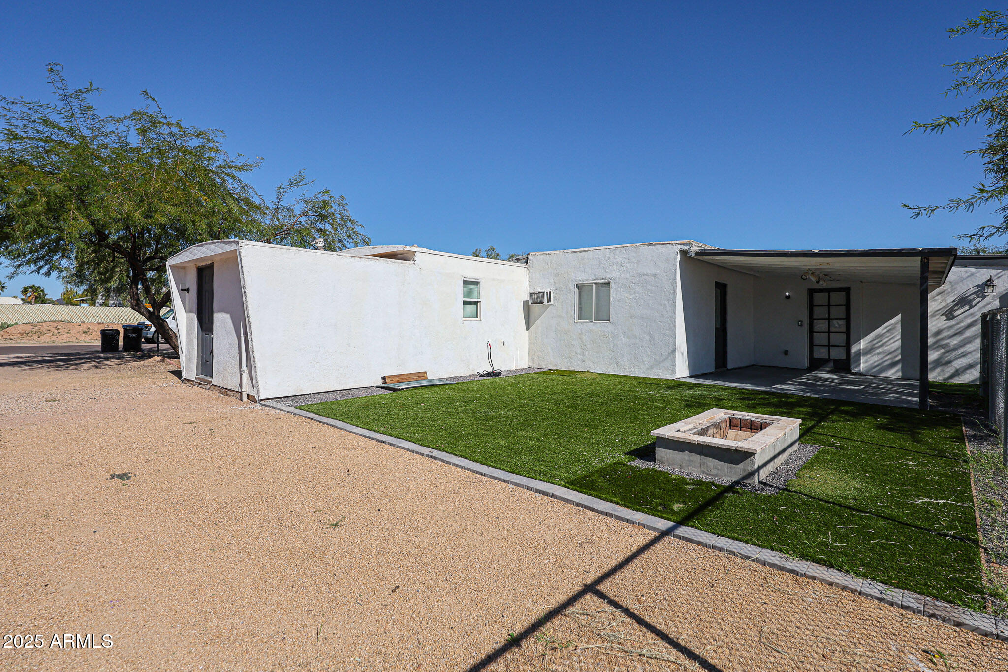 2839 East Marco Polo Road Phoenix, AZ 85050 - Photo 38 of 43 a view of a white house with a yard plants and a big tree