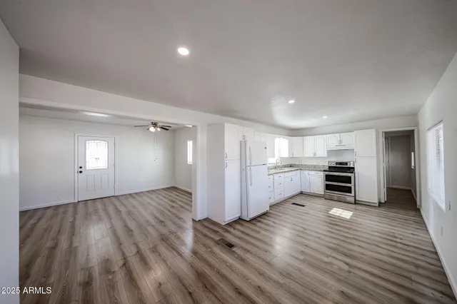 a kitchen with granite countertop cabinets appliances and wooden floor
