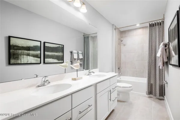 a bathroom with a double vanity sink toilet mirror and bathtub