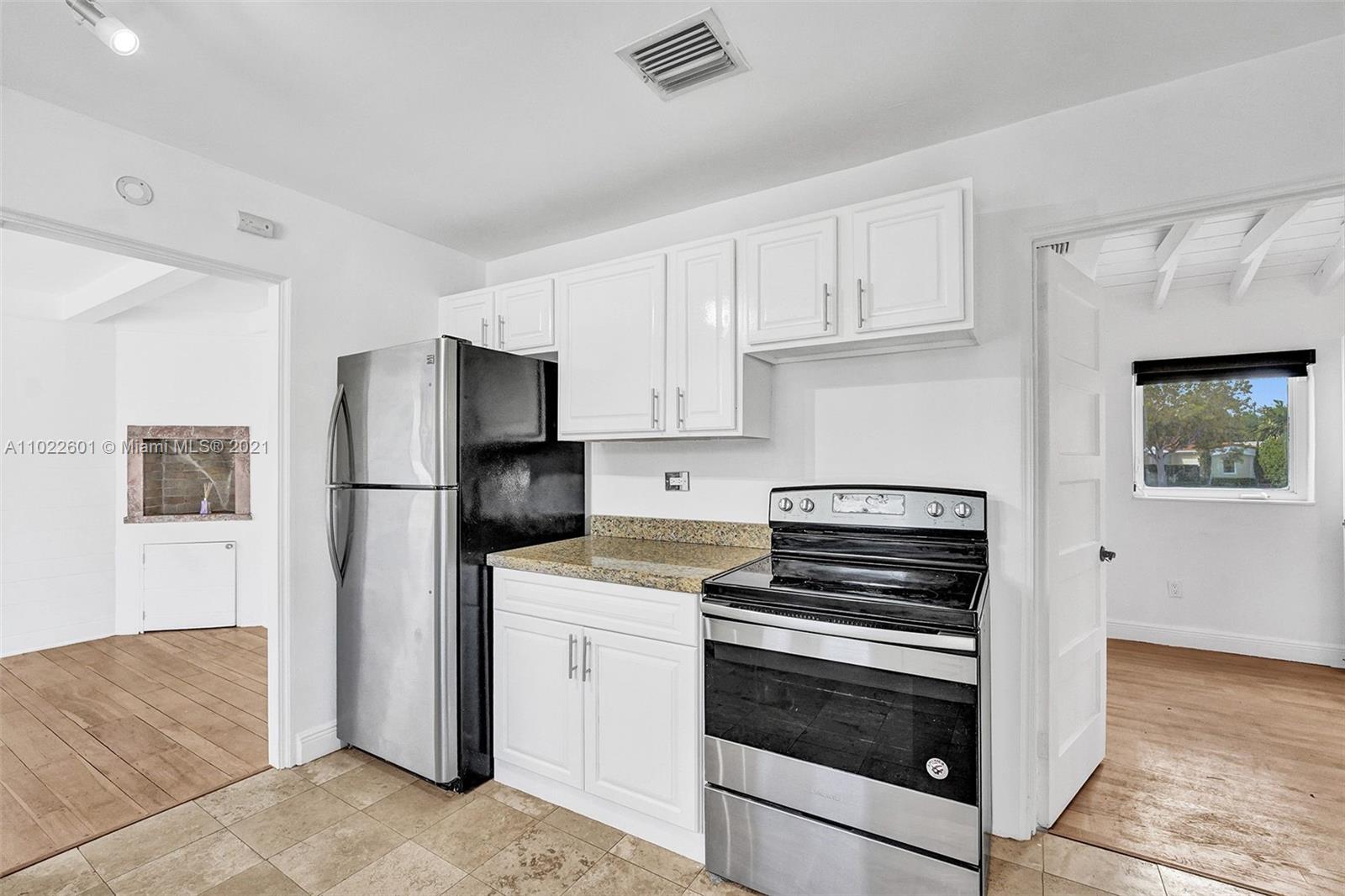 4717 Alton Road Miami Beach, FL 33140 - Photo 13 of 59 a kitchen with white cabinets and stainless steel appliances