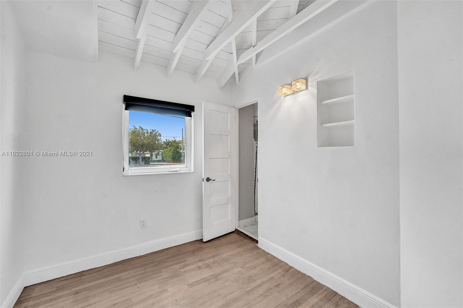 4717 Alton Road Miami Beach, FL 33140 - Photo 22 of 59 a view of an empty room with wooden floor and a window