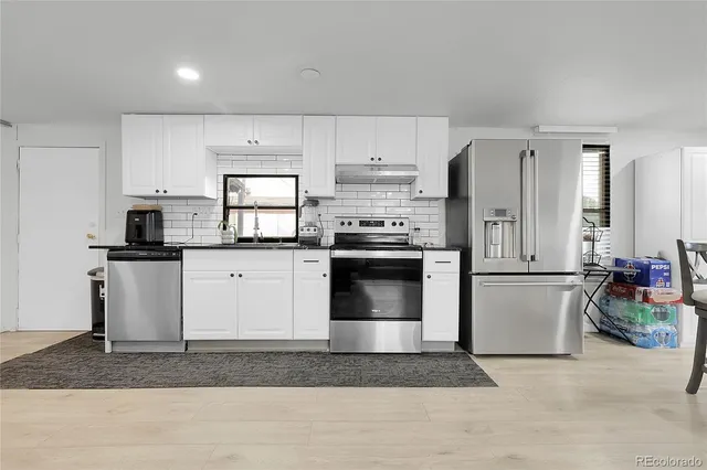 a kitchen with stainless steel appliances granite countertop a refrigerator sink stove and white cabinets
