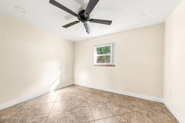 an empty room with a ceiling fan and window