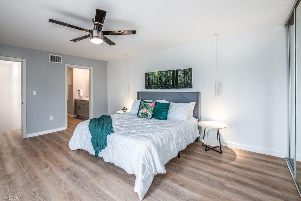 124 Lake Point Lane, Unit 2B Naples, FL 34112 - Photo 15 of 41 a bedroom with a bed and a chandelier