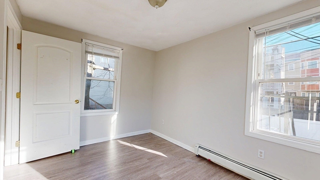 329 Paris Street, Unit 2 Boston, MA 02128 - Photo 14 of 24 an empty room with wooden floor and windows