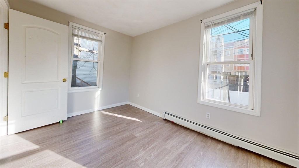 329 Paris Street, Unit 2 Boston, MA 02128 - Photo 16 of 24 an empty room with wooden floor and windows
