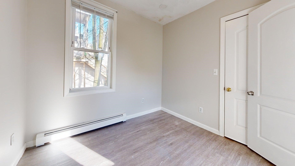 329 Paris Street, Unit 2 Boston, MA 02128 - Photo 19 of 24 an empty room with wooden floor and windows