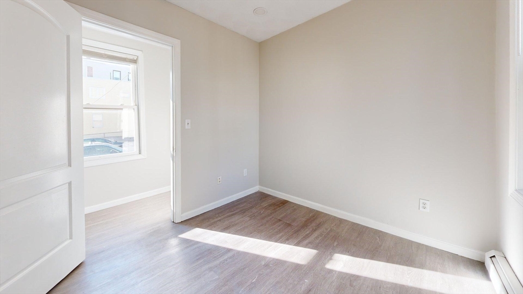 329 Paris Street, Unit 2 Boston, MA 02128 - Photo 20 of 24 an empty room with wooden floor and windows