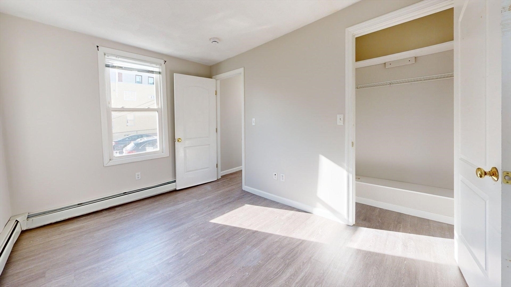 329 Paris Street, Unit 2 Boston, MA 02128 - Photo 3 of 24 a view of an empty room with wooden floor and a window