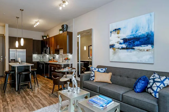 a living room with furniture kitchen view and a wooden floor